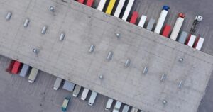 Arial view of a warehouse with many tractor trailers parked at the docks.