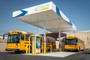 Two natural gas school buses fueling at a Trillium CNG station.