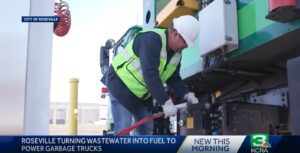 Man in yellow safety vest fuels a refuse truck with RNG